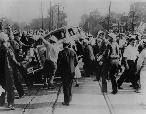 GM strikers overturn a vehicle outside the Fisher Body Plant, 1939