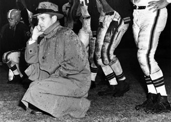 Paul Brown and players on sideline in the rain, 1952