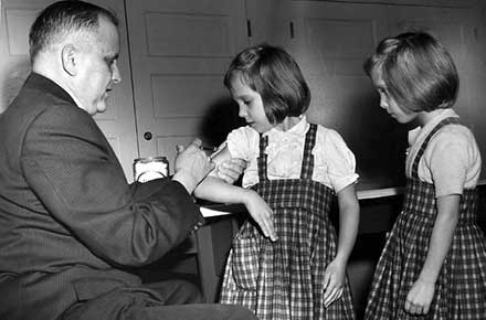 Dr. William Macy gives twin girls injections at the East End Neighborhood House, 1960