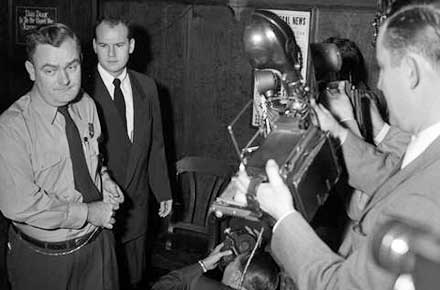 Deputy Sheriff James Kilroy leads Sam Sheppard to the courtroom, while the media looks on, 1954.
