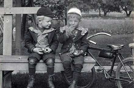 Two unidentified boys on bench, eating