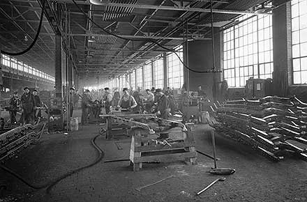Laborers assemble steel frames on factory floor