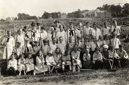 Group of student gardeners with tools, some dressed in sailor or midi shirts.