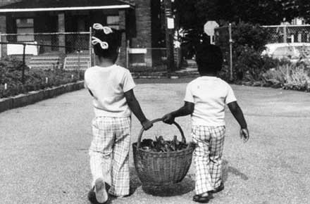 Two girls carry a basket of garden greens home from the school garden in Cleveland, Ohio